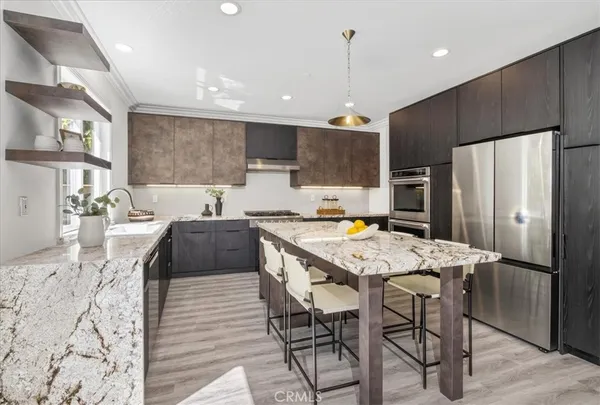 a kitchen with stainless steel appliances kitchen island granite countertop a refrigerator a stove a sink a dining table and chairs