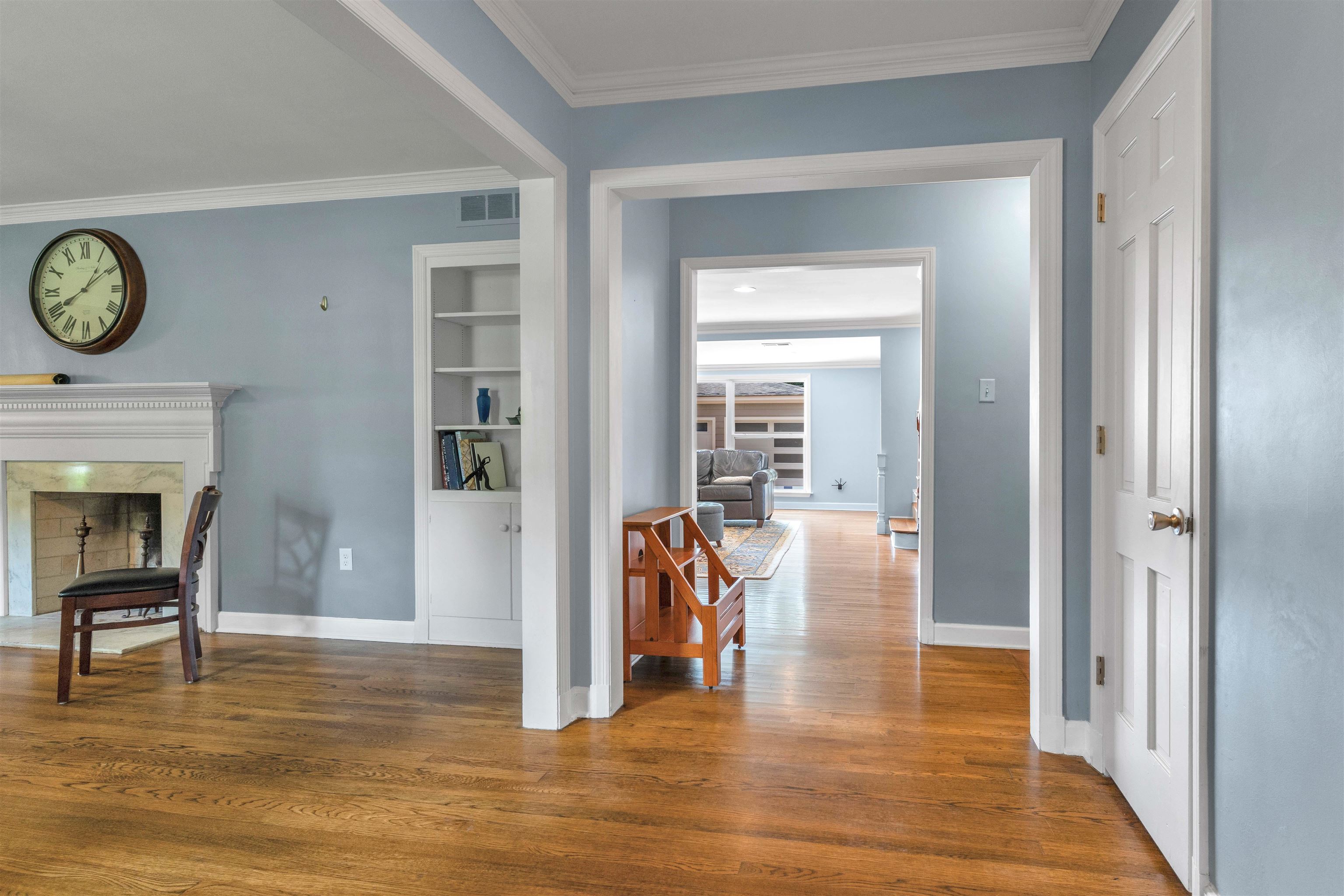 5187 South Angela Road Memphis, TN 38117 - Photo 6 of 39 Hardwood flooring throughout, featuring a white fireplace mantel, built-in shelving, and crown molding