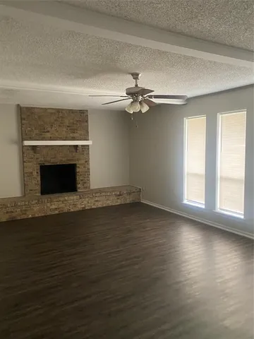 an empty room with wooden floor fireplace and windows