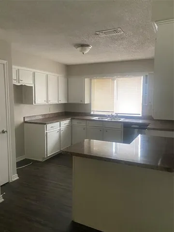 a large kitchen with stainless steel appliances granite countertop a sink a stove a microwave a counter space and cabinets