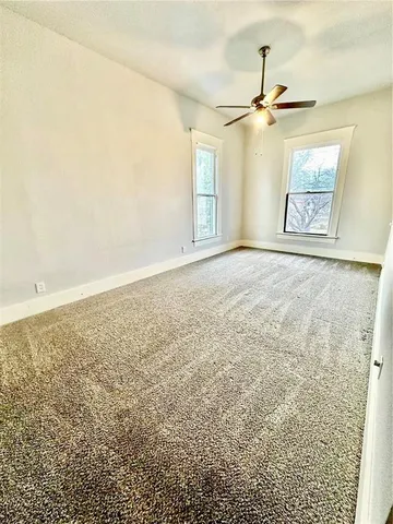 an empty room with windows and fan view