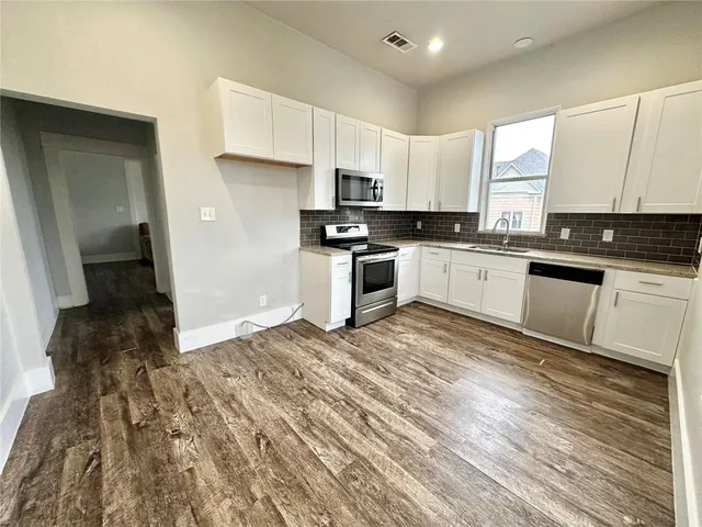 a kitchen with granite countertop a stove top oven a sink and white cabinets