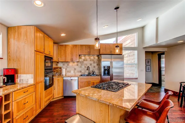 a kitchen with stainless steel appliances granite countertop a stove a sink and a refrigerator