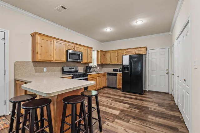 a kitchen with a refrigerator a stove top oven a sink dishwasher and wooden cabinets