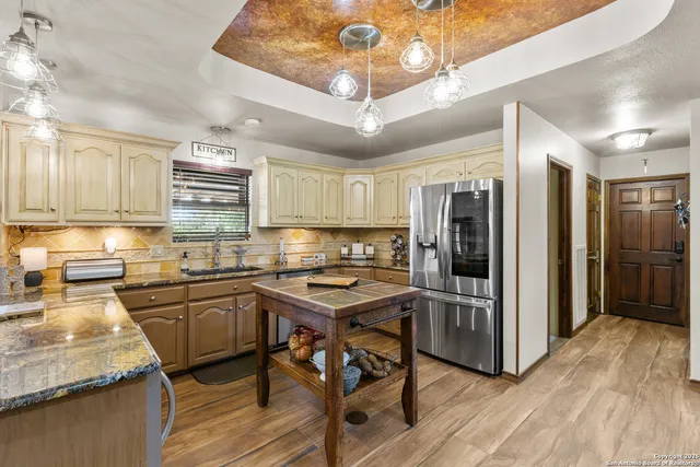 a kitchen with stainless steel appliances granite countertop a sink refrigerator and cabinets