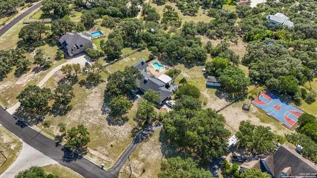 an aerial view of residential house with outdoor space and trees all around