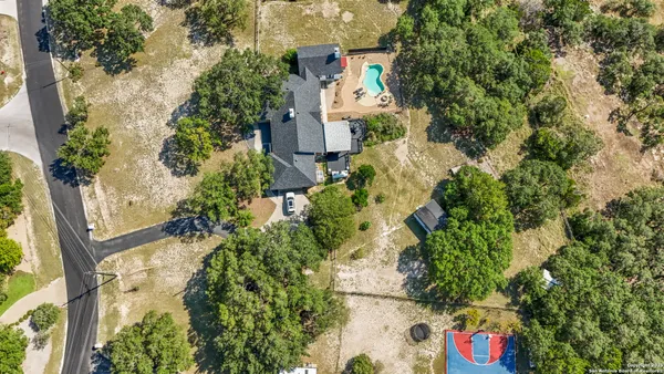an aerial view of residential house with outdoor space and trees all around