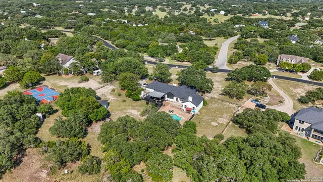 an aerial view of residential houses with outdoor space and trees