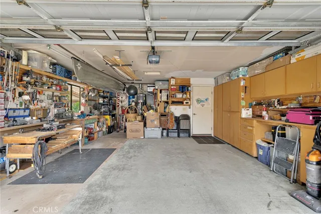 a view of a white house with a big yard plants and large tree