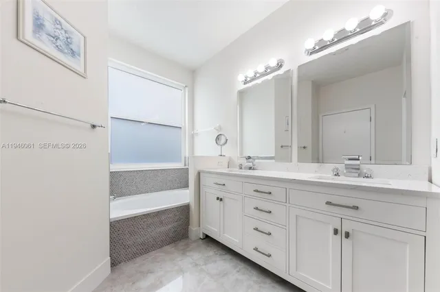 a bathroom with a double vanity sink a mirror and a bathtub