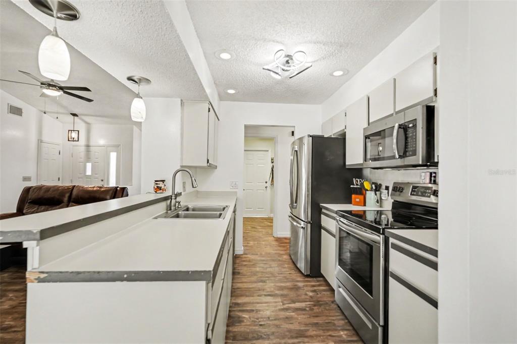4156 Weldon Avenue Spring Hill, FL 34609 - Photo 5 of 26 a kitchen with stainless steel appliances a sink stove refrigerator and cabinets