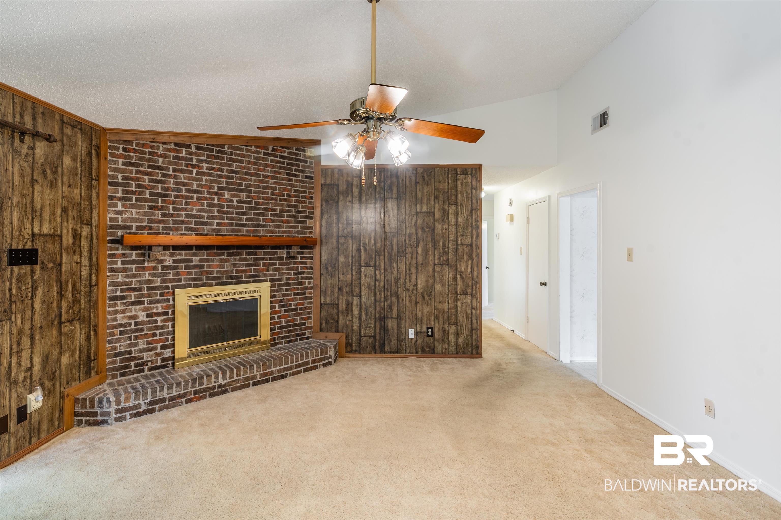 9751 Pine Knoll Road Mobile, AL 36608 - Photo 10 of 36 Unfurnished living room featuring wood walls, a fireplace, carpet, ceiling fan, and lofted ceiling