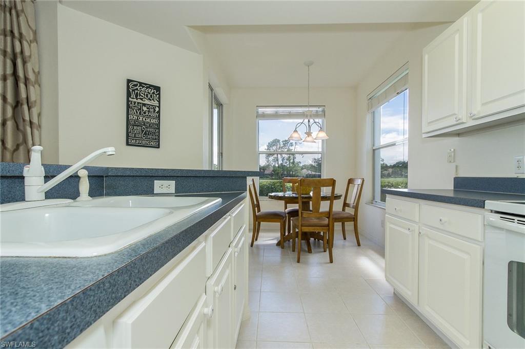 23770 Clear Spring Court, Unit 1402 Estero, FL 34135 - Photo 6 of 17 a kitchen with a sink dining table and chairs