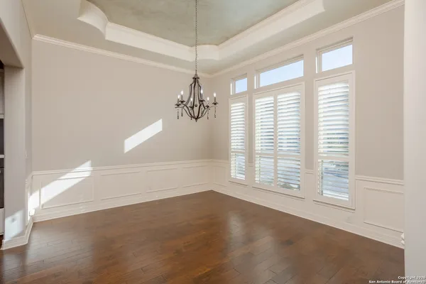 an empty room with windows and chandelier fan