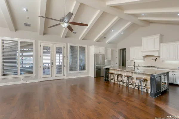 a open kitchen with stainless steel appliances granite countertop a stove top oven a dining table and chairs with wooden floor