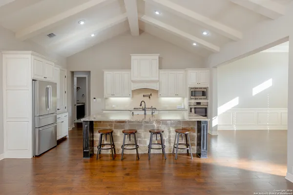 a kitchen with stainless steel appliances a dining table chairs and refrigerator
