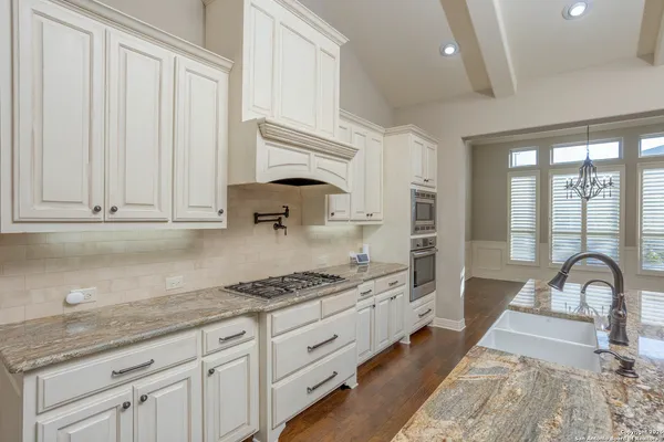 a kitchen with stainless steel appliances granite countertop a stove a sink and a white cabinets