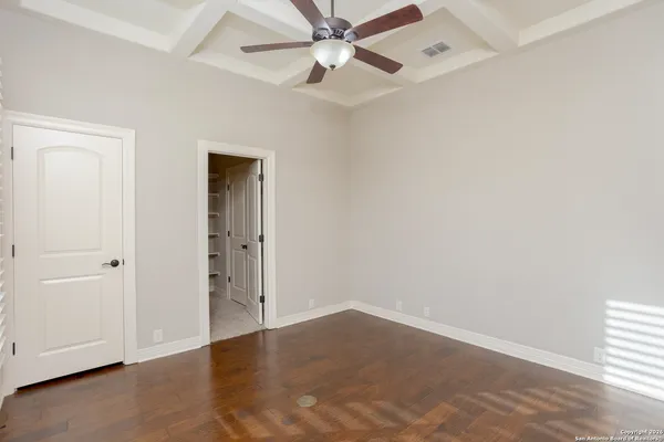 an empty room with wooden floor closet and windows