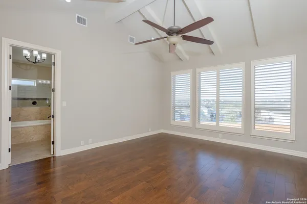an empty room with wooden floor fan and windows