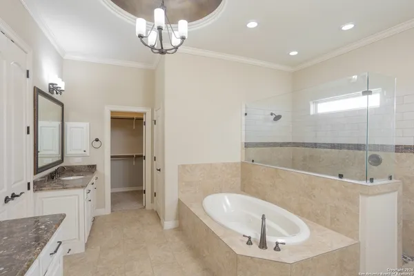 a bathroom with a tub a sink and a large mirror