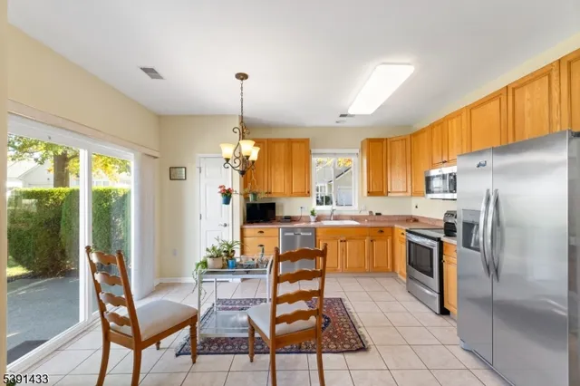 a kitchen with stainless steel appliances kitchen island granite countertop a refrigerator a stove a sink dishwasher with a dining table and chairs