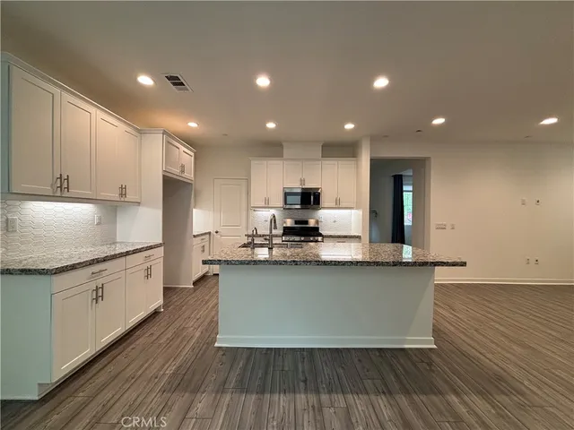 a kitchen with stainless steel appliances granite countertop a stove a sink and a refrigerator
