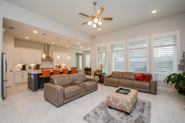 a living room with furniture ceiling fan and a large window