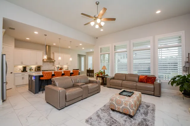 a living room with furniture ceiling fan and a large window