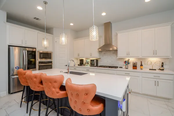 a kitchen with stainless steel appliances kitchen island granite countertop a dining table chairs sink and cabinets