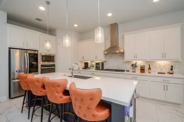 a kitchen with stainless steel appliances kitchen island granite countertop a dining table chairs sink and cabinets