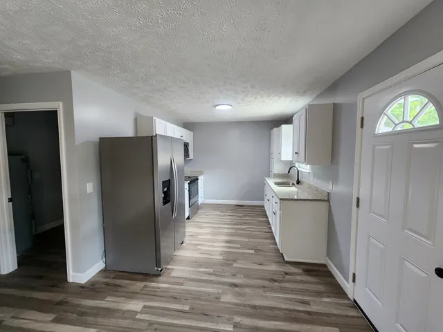 a view of a kitchen with refrigerator and wooden floor