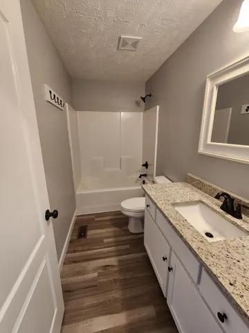 a bathroom with a granite countertop sink a toilet a tub and shower