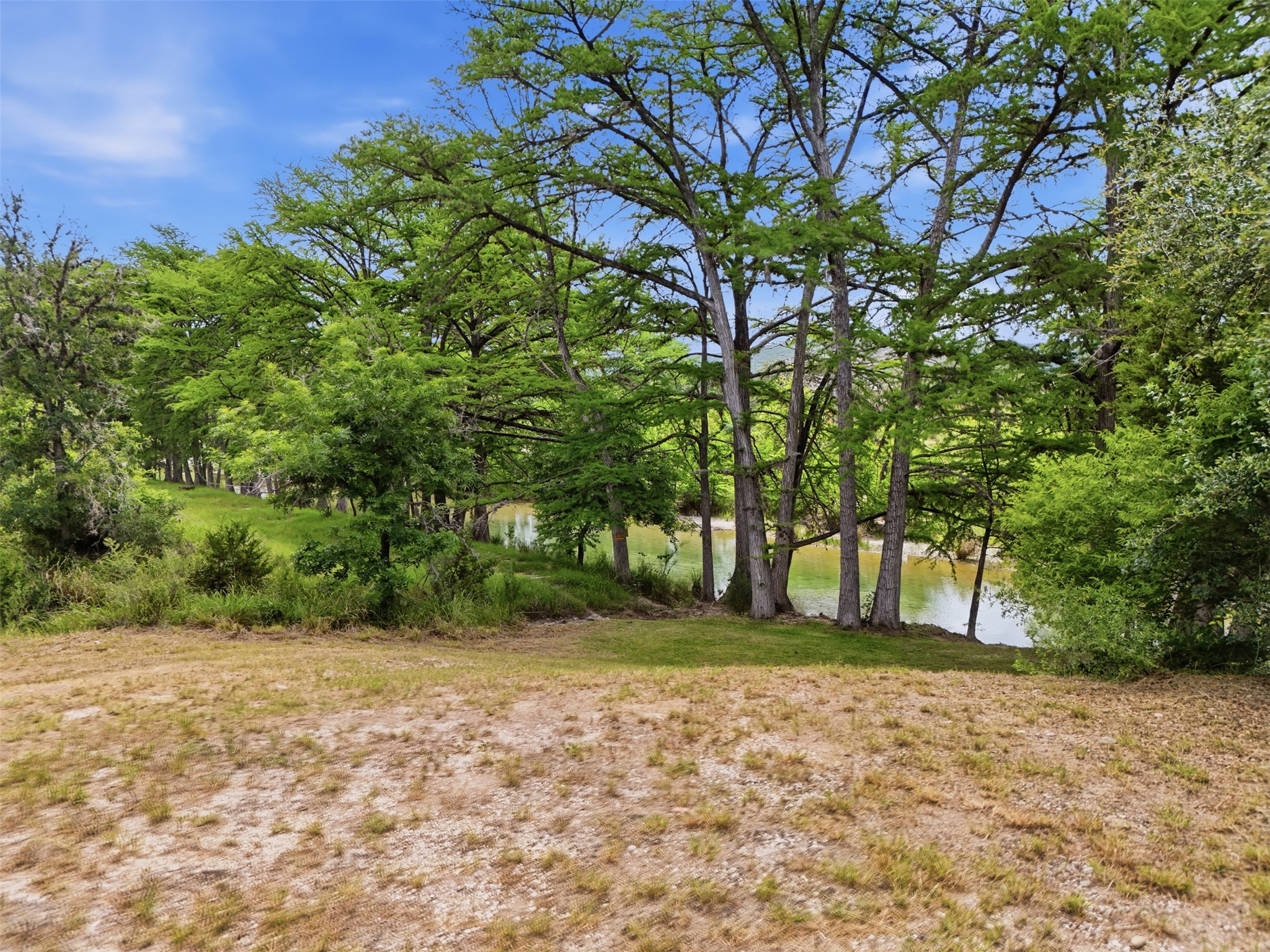 1260 Magers Road Concan, TX 78838 - Photo 5 of 40 A tranquil river flows past a verdant landscape, offering a picturesque and serene natural setting.