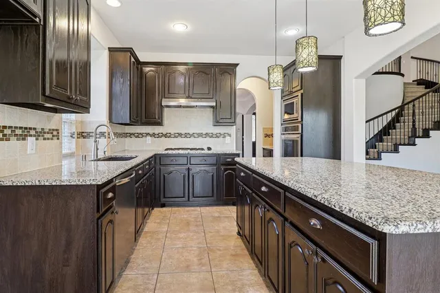 a kitchen with stainless steel appliances granite countertop a sink stove and cabinets
