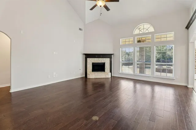 an empty room with wooden floor fireplace and windows