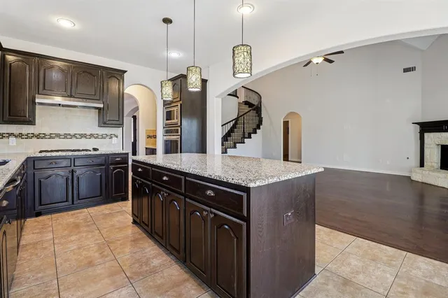 a kitchen with stainless steel appliances granite countertop a sink a stove and a wooden floors
