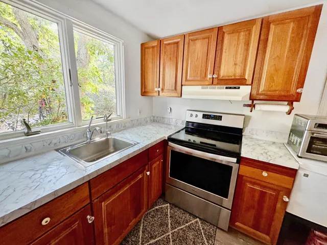 a kitchen with granite countertop wooden cabinets a sink and a window