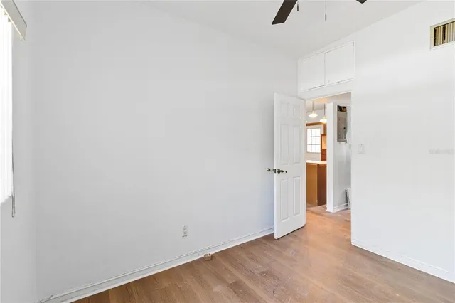an empty room with wooden floor fan and windows
