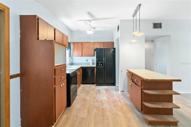 a kitchen with stainless steel appliances a refrigerator and a wooden floor