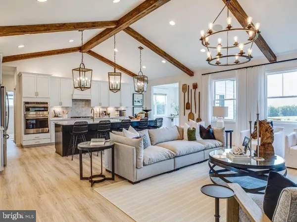 a living room with couches a dining table and kitchen view with wooden floor