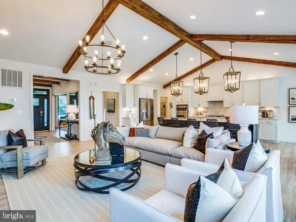 a living room with furniture kitchen view and a chandelier