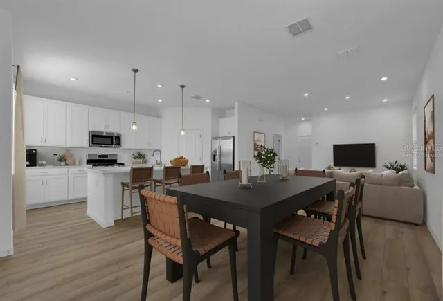 a kitchen with a dining table chairs stainless steel appliances and cabinets