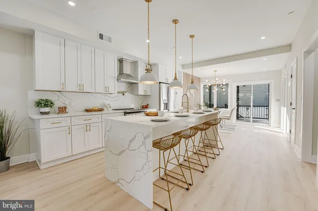 a kitchen with stainless steel appliances granite countertop a stove a sink and white cabinets with wooden floor