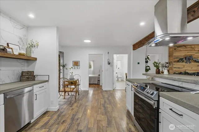 a kitchen with stainless steel appliances a stove a sink dishwasher and cabinets with wooden floor