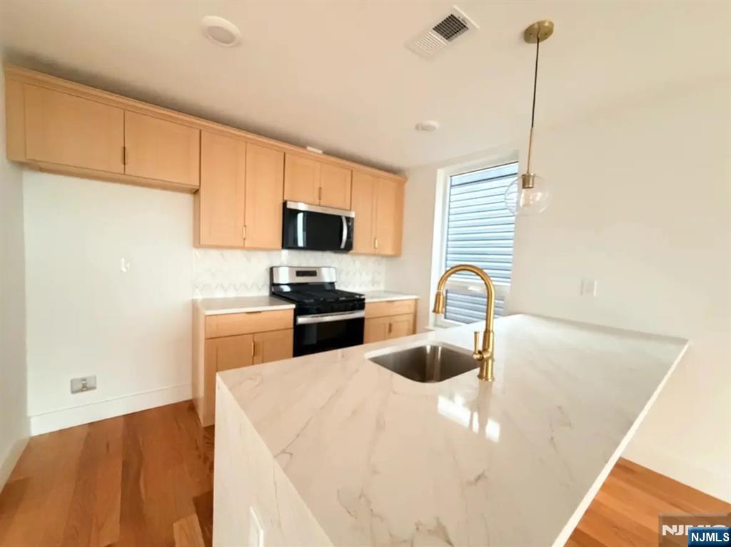 39 South 7th Street, Unit 2 3 Newark, NJ 07107 - Photo 3 of 13 a kitchen with stainless steel appliances a stove top oven a sink a dining table and chairs with wooden floor