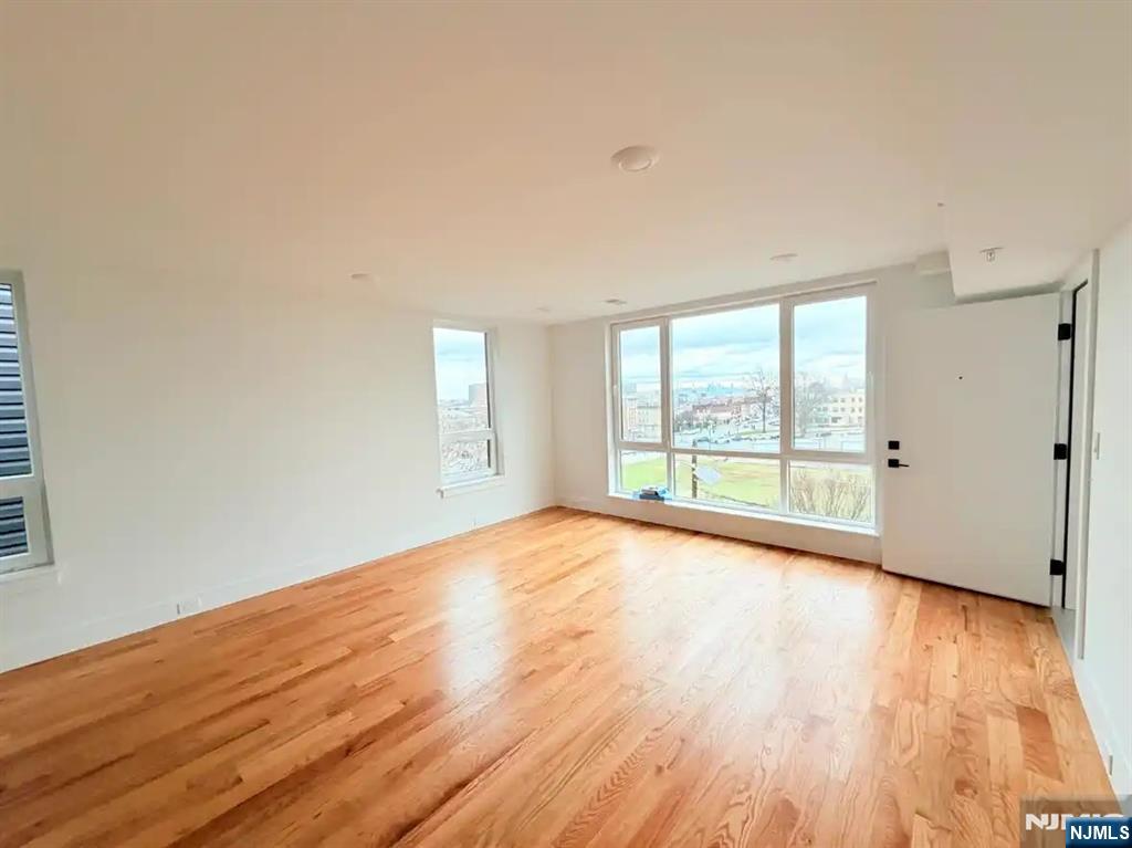 39 South 7th Street, Unit 2 3 Newark, NJ 07107 - Photo 4 of 13 a view of an empty room with wooden floor and a window