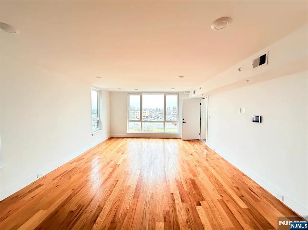 39 South 7th Street, Unit 2 3 Newark, NJ 07107 - Photo 5 of 13 a view of an empty room with wooden floor and a window