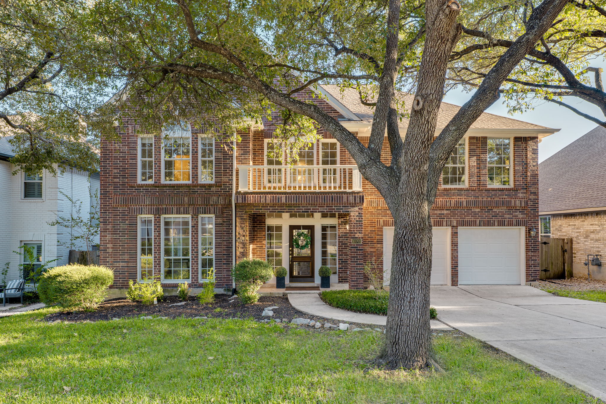 10701 Redmond Road Austin, TX 78739 - Photo 1 of 1 View of front facade with a balcony, brick siding, a front lawn, and driveway