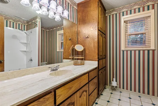a bathroom with a granite countertop sink a large mirror and a shower