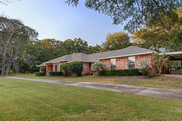 a front view of house with yard and trees in the background